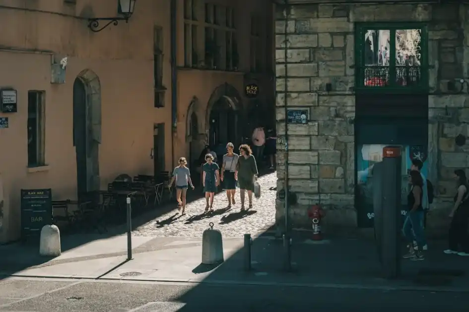 A group of people walking down a street next to tall buildings